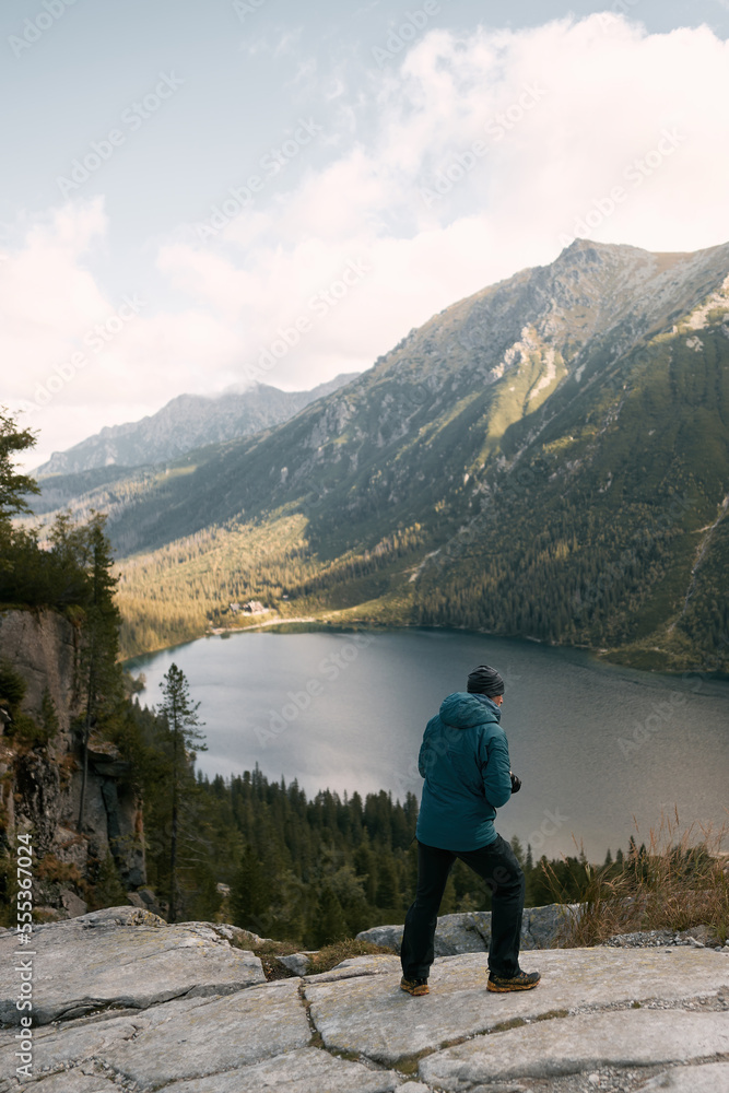 Photographer is taking photos of beautiful mountain nature with the lake. Travel and active lifestyle concept.Young man photographer taking photographs with a digital mirrorless camera in a mountains