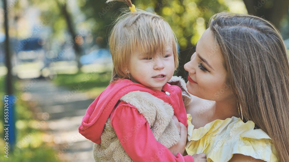 A mother hugs her young daughter in the park in the summer. A mother hugs her young daughter in the park in the summer.