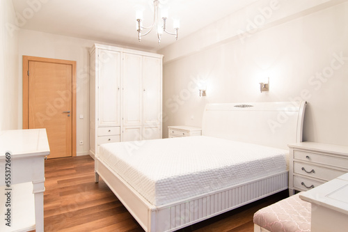 Gorgeous bed room in classic style with wooden floor and white furniture