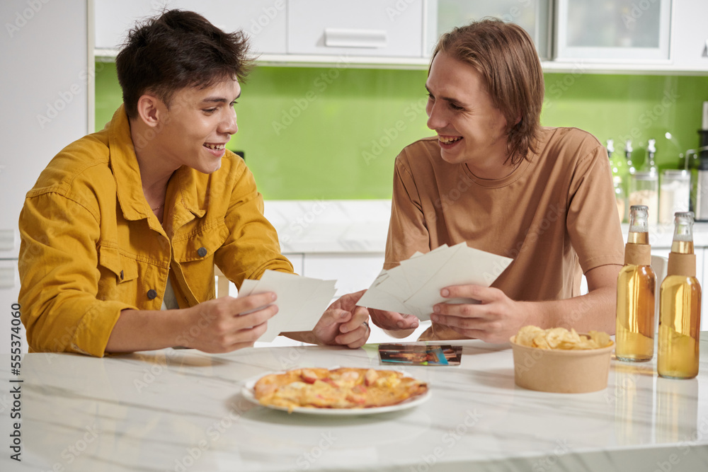 Joyful best friends discussing printed photos from summer vacation Joyful best friends discussing printed photos from summer vacation
