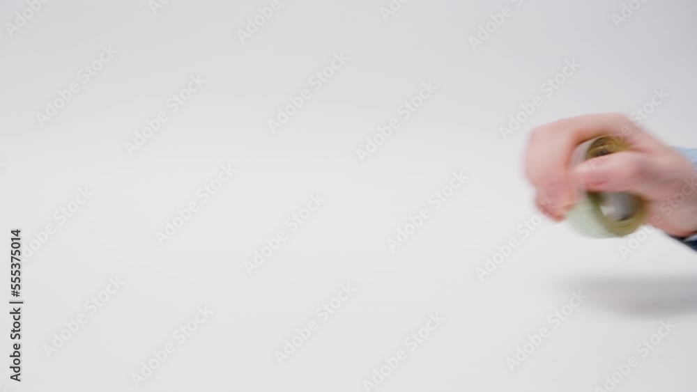 Bribery and stock market. American dollars rolled up roll across table and woman's hand grabs money. Close-up. White background. Concept of investment, banking and finance