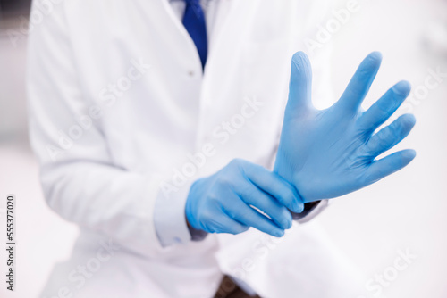 Doctor putting on protective latex gloves