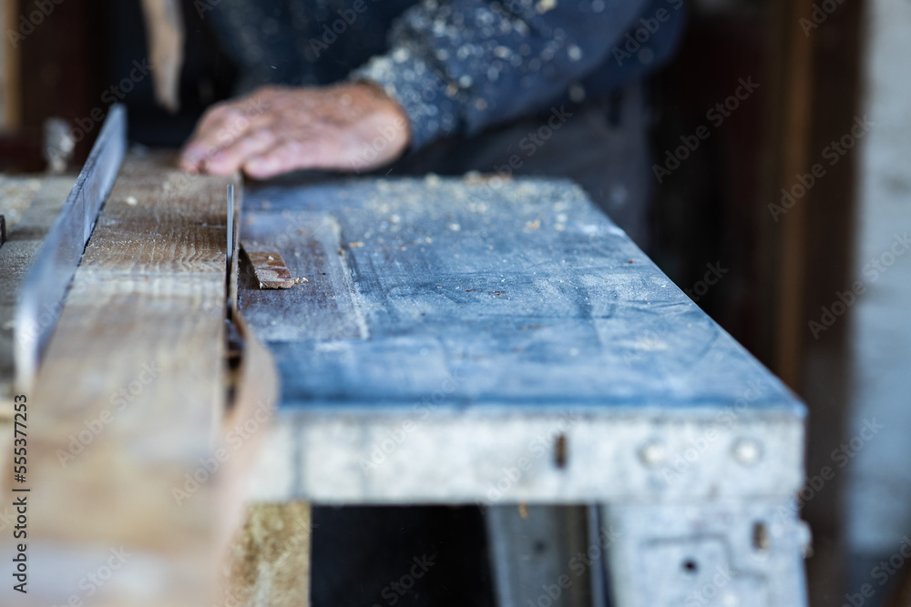 close-up photo of a circular saw cutting a wooden batten.in the blurred background is a worker's hand holding a wooden lath close-up photo of a circular saw cutting a wooden batten.in the blurred background is a worker's hand holding a wooden lath
