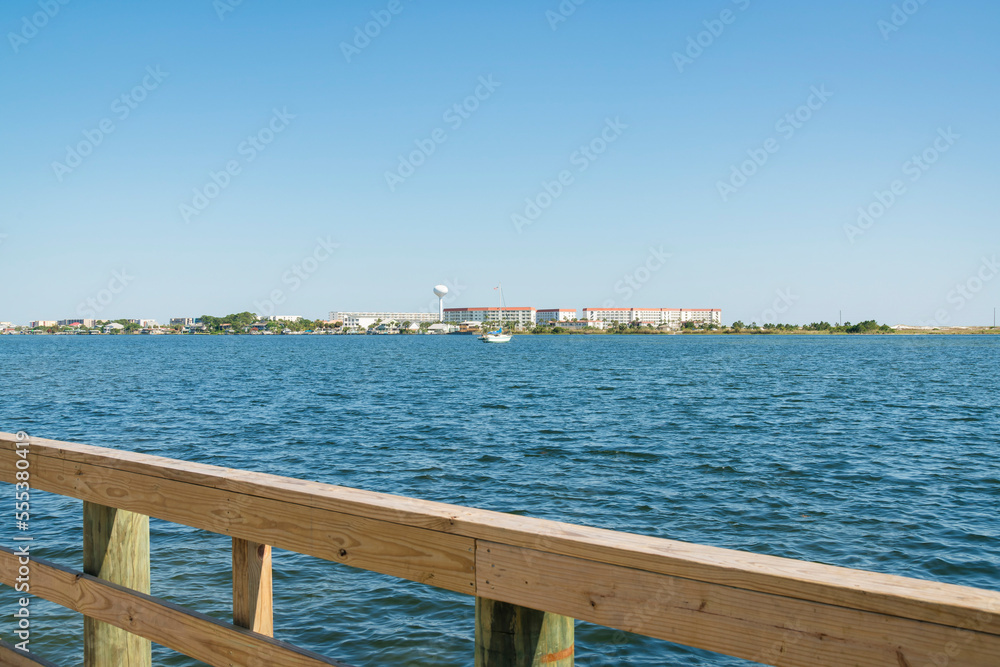 Views of buildings against the clear sky from a pier with wood handrails in Destin, Florida