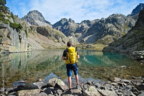Man facing away contemplates the Ibones de Arriel and surrounding peaks in the Spanish Pyrenees, photo
