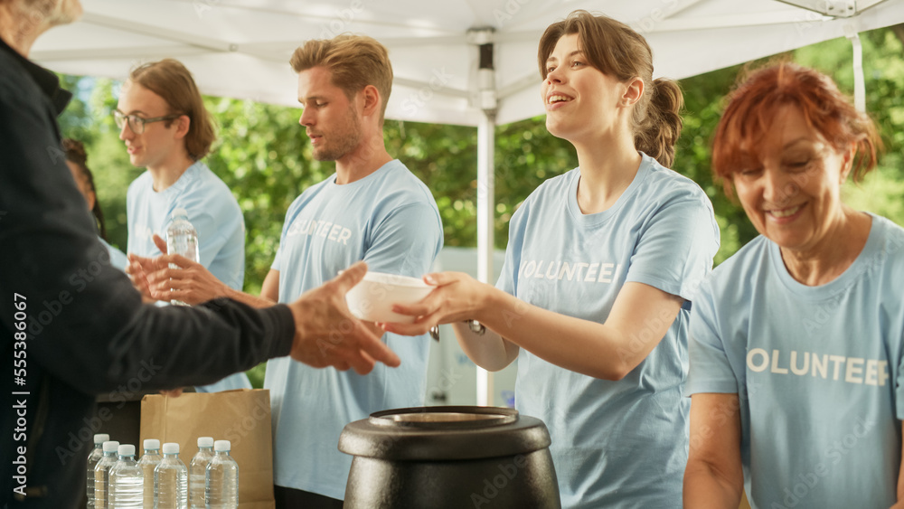 The Concept of Giving: Homeless People Reach Out To Free Volunteer Meals from Multiethnic Team of Volunteers. Humanitarian Aid Charity Workers Serve Meals to People in Need. The Concept of Giving: Homeless People Reach Out To Free Volunteer Meals from Multiethnic Team of Volunteers. Humanitarian Aid Charity Workers Serve Meals to People in Need.
