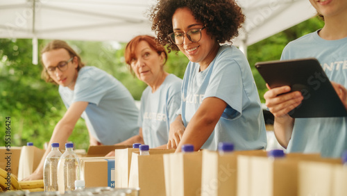 Portrait of a Happy Young Black Female Preparing Free Food Rations Together with Other Volunteers. Charity Workers and Members of the Community Work in Local Humanitarian Aid Donation Center.