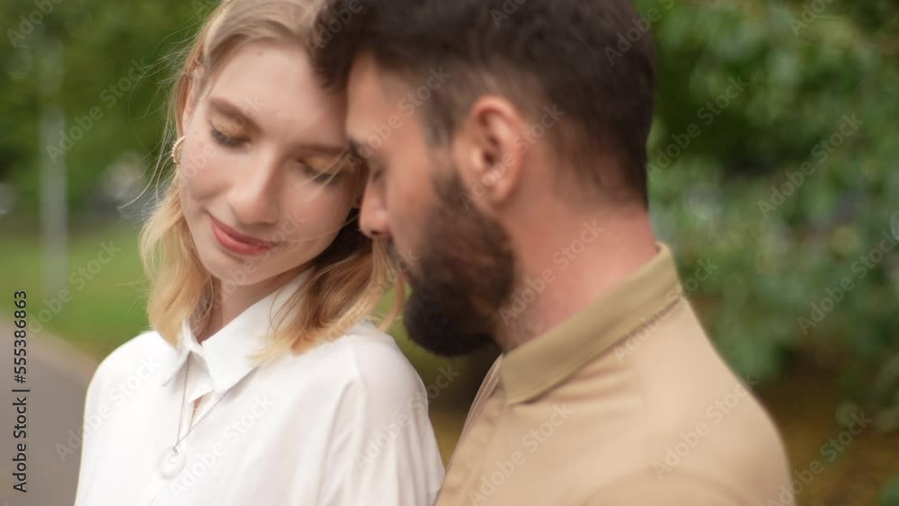 Close-up of dreamy young family couple standing with closed eyes feeling tenderness, enjoying their meeting during free time outdoors. Bearded handsome man embracing charming woman on city street. Close-up of dreamy young family couple standing with closed eyes feeling tenderness, enjoying their meeting during free time outdoors. Bearded handsome man embracing charming woman on city street.