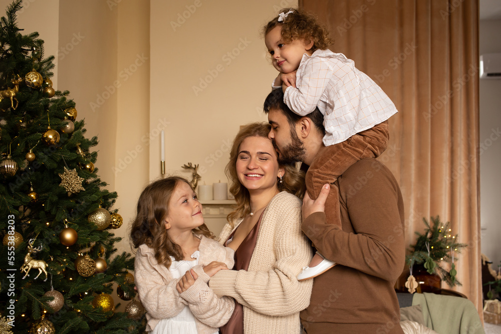 parents and children smile on a background of Christmas trees in the interior of the house