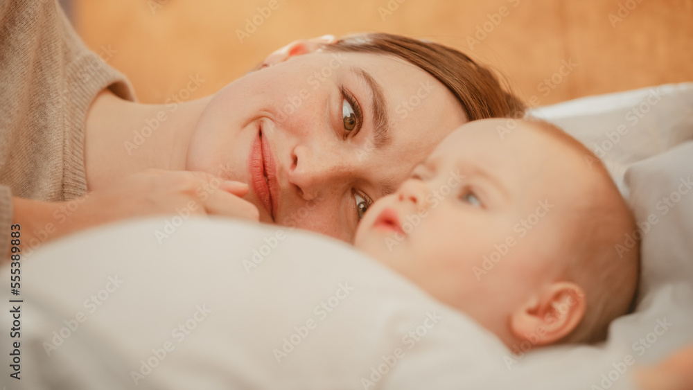 Loving Young Beautiful Mother Playing and Soothing Adorable Baby in Bed. Smiling Caring Mom and Cute Little Infant Child Cuddling in Bedroom. Motherhood Tender Moments. Loving Young Beautiful Mother Playing and Soothing Adorable Baby in Bed. Smiling Caring Mom and Cute Little Infant Child Cuddling in Bedroom. Motherhood Tender Moments.
