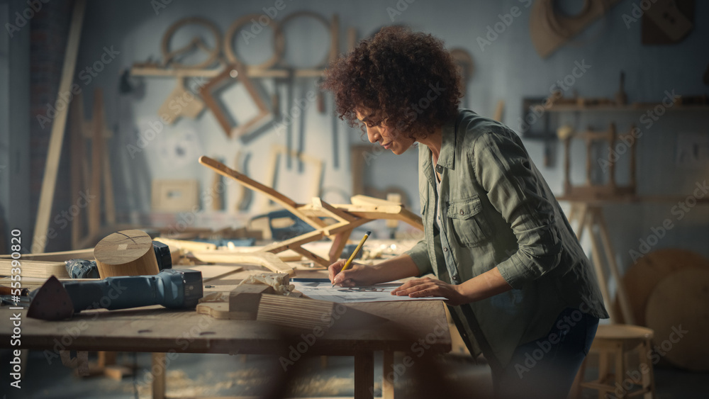Portrait of a Young Beautiful Carpenter Checking a Blueprint and Starting to Assemble a Wooden Chair. Professional Furniture Designer Working in a Studio in Loft Space with Tools on the Walls.