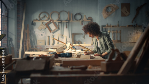 Multiethnic Artisan Woodworker Marking Out Dimensions on a Blueprint and Starting to Assemble a Wooden Chair. Black Female Carpenter Working in a Studio in Loft Space with Tools on the Walls.
