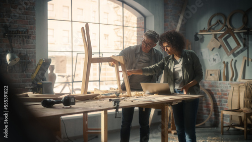 Wallpaper Mural Small Business Owners of a Furniture Workshop Using Laptop Computer and Discussing the Design of a New Wooden Chair. Middle Age Carpenter and a Young Female Apprentice Working in Loft Studio. Torontodigital.ca