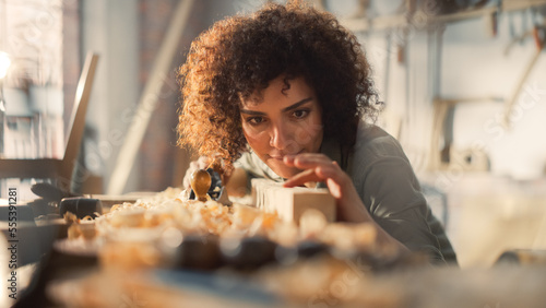 Close Up Portrait of a Young Female Artisan Carpenter Using Hand Plane to Shape a Wood Bar. Beautiful Artist Working on a Project in a Woodworking Workshop. photo