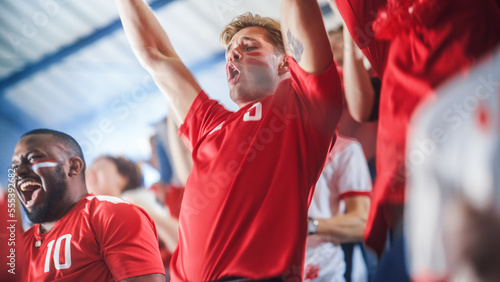 Sport Stadium Sport Event: Intense Caucasian Man Cheering, Whistling. Crowd of Fans with Painted Faces Stand up, Cheer, Shout for Red Soccer Team to Win, Celebrate Scoring Goal, Championship Victory