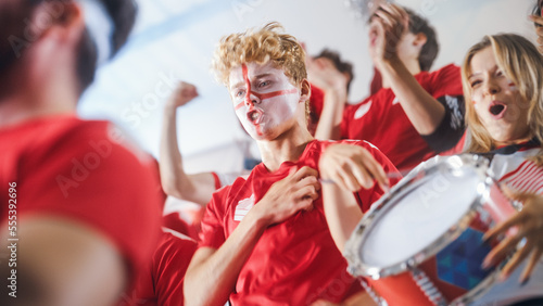 Sport Stadium Sport Event: Intense Caucasian Man Cheering, Whistling. Crowd of Fans with Painted Faces Stand up, Cheer, Shout for Red Soccer Team to Win, Celebrate Scoring Goal, Championship Victory © Gorodenkoff