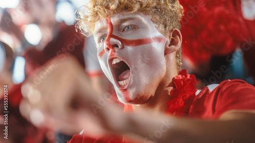 Fototapeta Naklejka Na Ścianę i Meble -  Sport Stadium Sport Event: Close-up Portrait of Handsome Caucasian Man with Painted Cheering for Red Team to Win, Screaming in Celebration of a Victory. International Championship, World Tournament