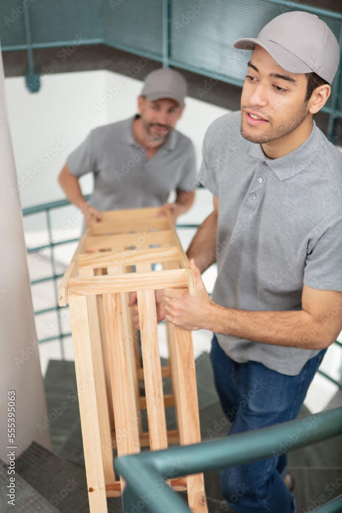 people carrying a bookshelf in an apartment people carrying a bookshelf in an apartment