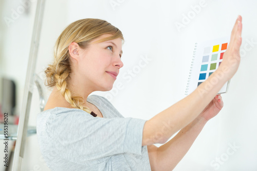 woman next to a wall looking to color samples
