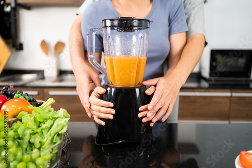 Crop image of happy Asian couple enjoy using blender machine for making healthy vegan smoothie on the kitchen counter. Couple making vegan smoothie together at home for a healthy lifestyle.