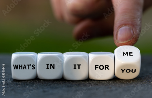 Hand turns dice and changes the expression 'what's in it for you' to 'what's in it for me'. photo