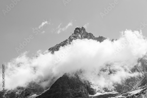 Black and white photo of Aiguille du Midi between clouds at French Alps.