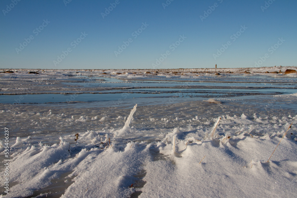 Arctic landscape - frozen arctic tundra in Nunavut over a snow covered waterbody on a clear cold day, near Arviat, Nunavut
