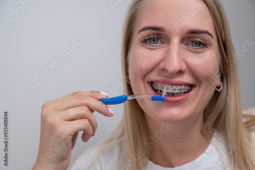 Caucasian woman cleaning her teeth with braces using a brush. 