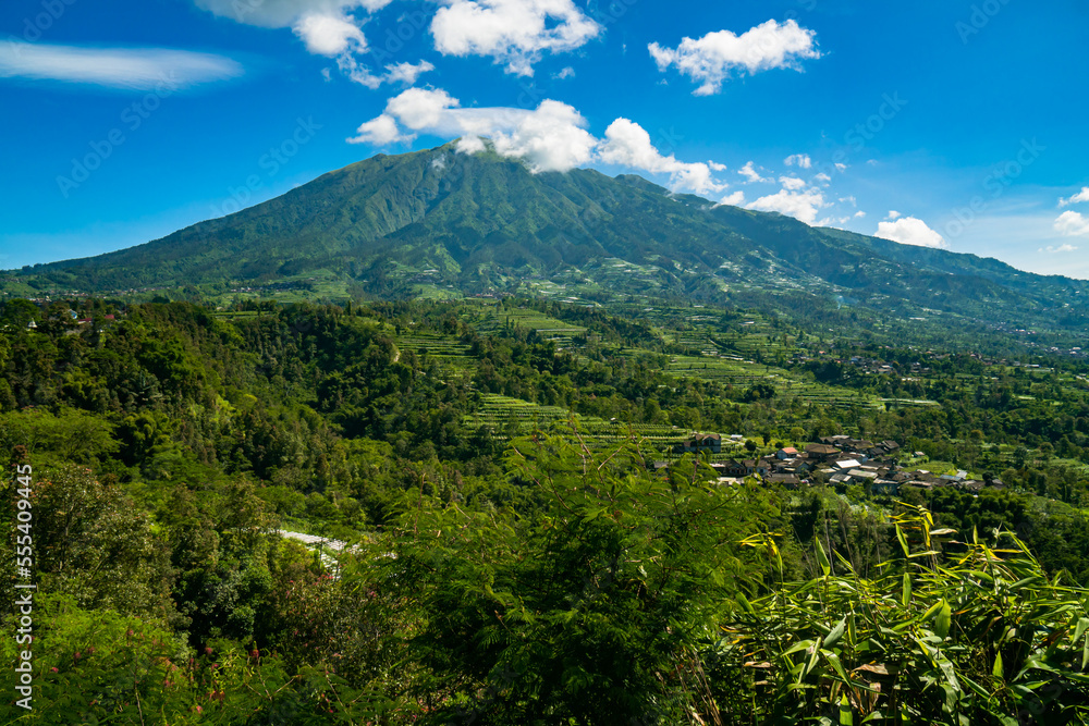 Obraz premium The beauty of Mount Merbabu seen from Ketep Pass, a mountain covered with green hills and blue sky and a few clouds that spoil the eyes of visitors