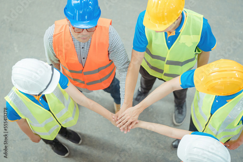 actory workers stacking hands together in warehouse or storehouse . Logistics , supply chain and warehouse business concept .. photo