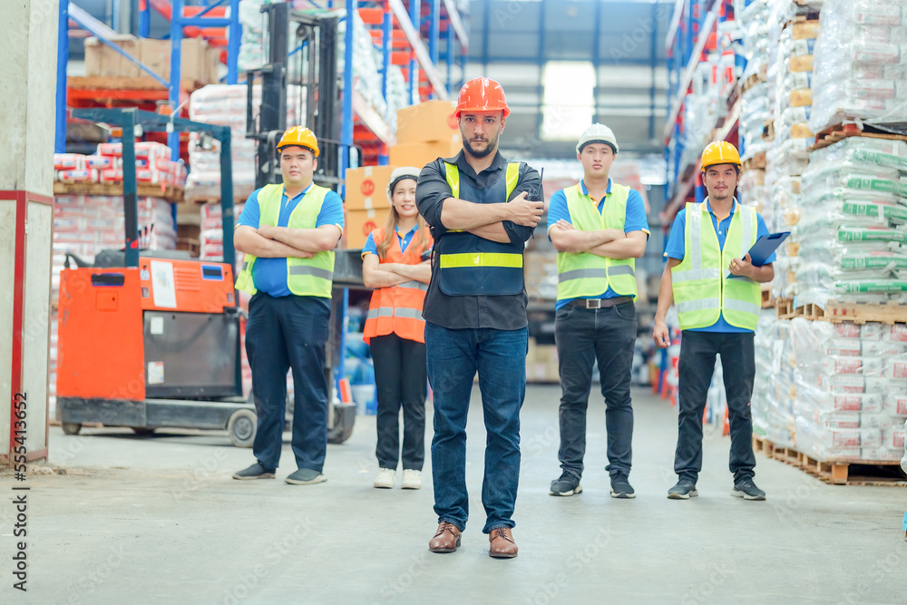 Fototapeta premium Smiling warehouse team with arms crossed in a large warehouse ,Logistics industry concept.