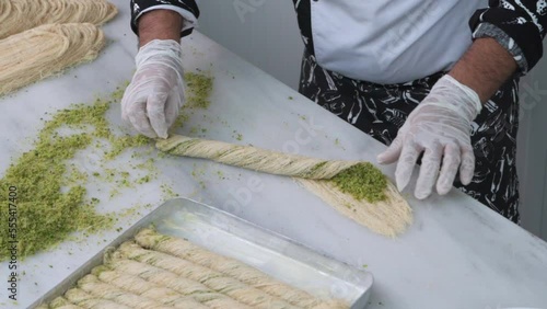 Chef at an oriental food stall in the market making Middle-Eastern Delicious traditional dessert kadayif kunefe with pistachios. Turkish dessert kadayif kunefe.
 photo