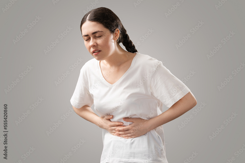 Stomach pain. Suffering young Caucasian woman holds her hands to her stomach. Menstruation and indigestion. The concept of gynecology, diet and diarhhea Stomach pain. Suffering young Caucasian woman holds her hands to her stomach. Menstruation and indigestion. The concept of gynecology, diet and diarhhea