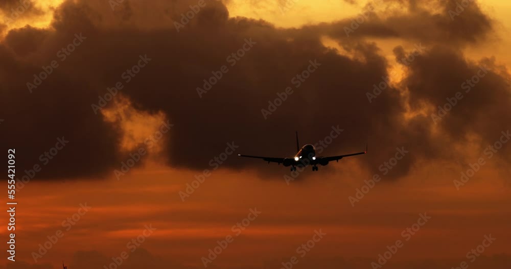 Silhouette of passenger plane that lands at airport at epic magnificent sunset. Dark brown silhouette of twin engine aircraft landing against orange sunset sky. Airplane flies through evening sky Silhouette of passenger plane that lands at airport at epic magnificent sunset. Dark brown silhouette of twin engine aircraft landing against orange sunset sky. Airplane flies through evening sky