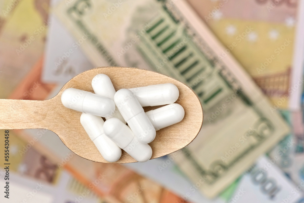 Pills in Wood Spoon on Paper Currency Background. Capsules, Vitamin