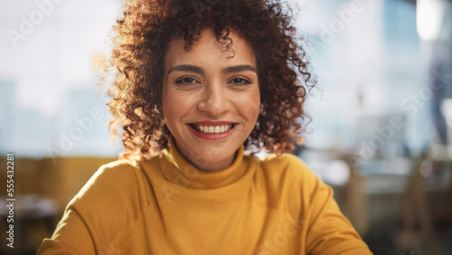 Portrait of an Attractive Arab Female in Creative Agency. Young Stylish Manager with Curly Hair Smiling, Looking at Camera. Manager Working in Modern Company.