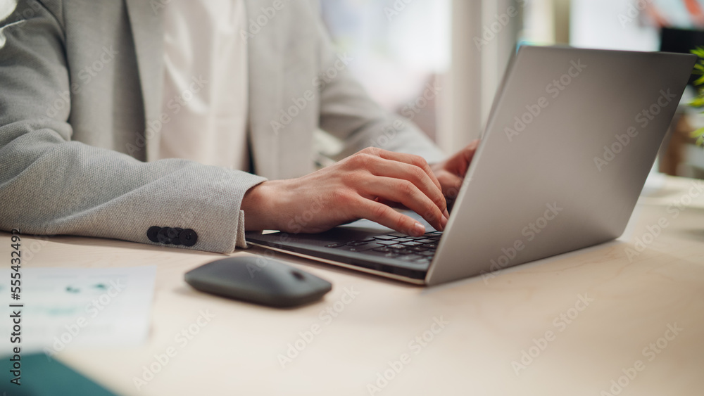 Manager Sitting at a Desk in Creative Office. Focus On Hands of a Young Stylish Man in a Jacket Using Laptop Computer in Marketing Agency. Employee Typing and Using Mouse Manager Sitting at a Desk in Creative Office. Focus On Hands of a Young Stylish Man in a Jacket Using Laptop Computer in Marketing Agency. Employee Typing and Using Mouse