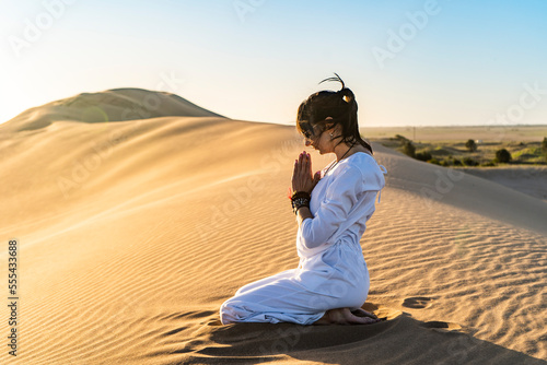 Woman gesticulating namaste in desert