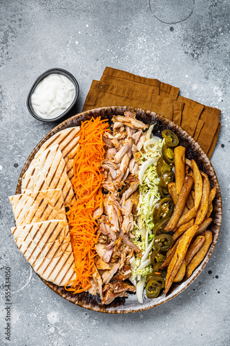 Chicken Shawarma Doner kebab on a plate with french fries, vegetables and salad. Gray background. Top view
