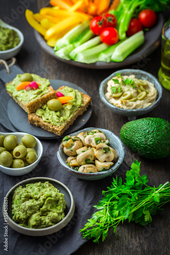 Vegan raw food snacks with fresh juicy vegetables, avocado dip and humus