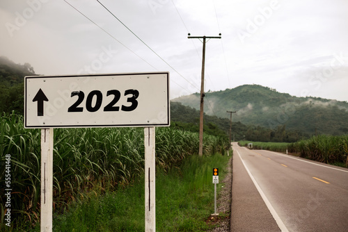 white roadside sign says 2023 with an arrow pointing straight ahead. , Concept of New year 2023.