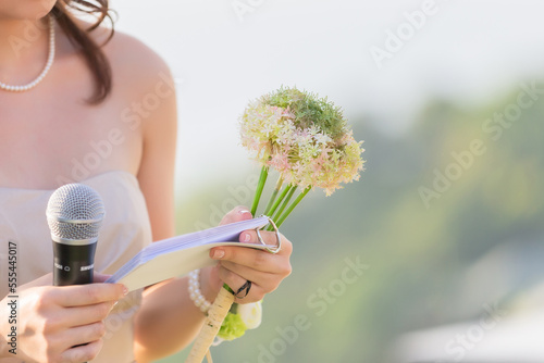 A bouquet of flowers in the hands of a female host, holding a microphone, waiting for the schedule to report the order of the event. photo