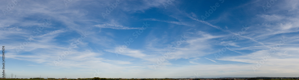 Blau-weißer Wolkenhintergrund mit Cirrostratuswolken und Kondensstreifen
