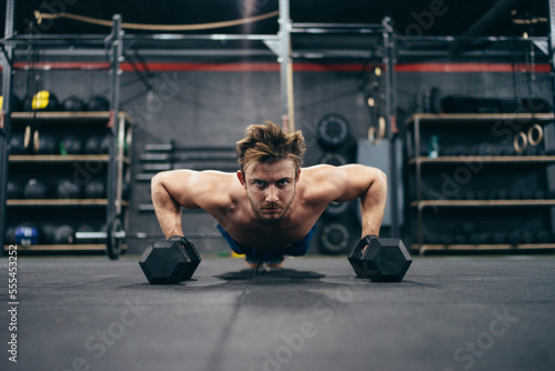 Strong man doing push-ups using dumbbells