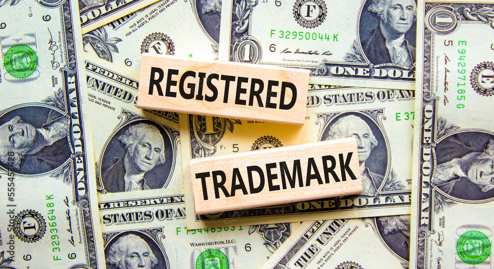 Registered trademark symbol. Concept word Registered trademark on wooden blocks. Beautiful background from dollar bills. Business and registered trademark concept. Copy space.
