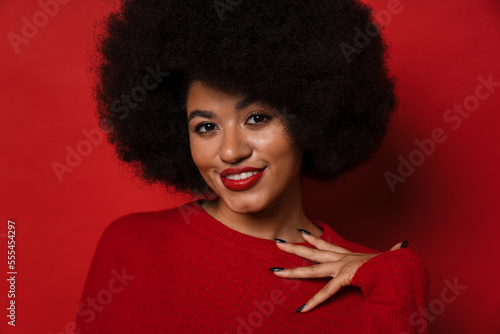 Attractive smiling afro woman posing isolated over red studio wall