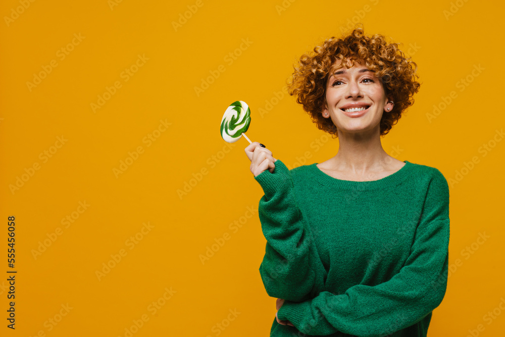 Curly ginger woman smiling while posing with lollipop Curly ginger woman smiling while posing with lollipop