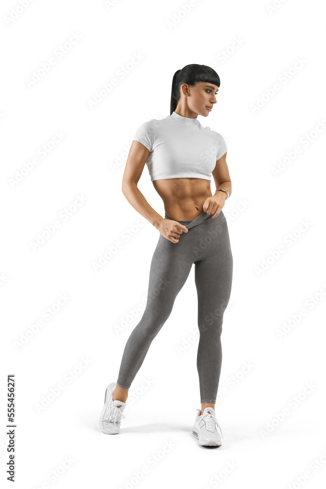 Athletic muscular young female bodybuilder muscular slim body, abs. Pleasure after sports work out, exercise. Blank sportswear, gray leggings and a white crop top, ponytail hairstyle.