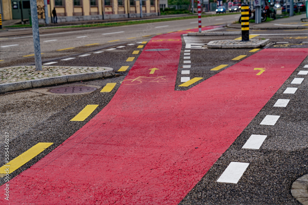 Red road marking bicycle lane with junction at Swiss City of Basel on a cloudy and rainy autumn day. Photo taken October 3rd, 2022, Basel, Switzerland.
