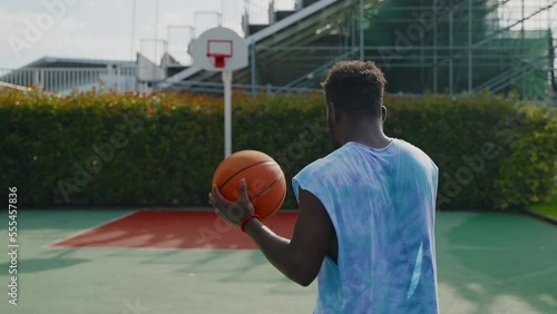 african american guy is walking on street basketball ground, rear view, slow motion